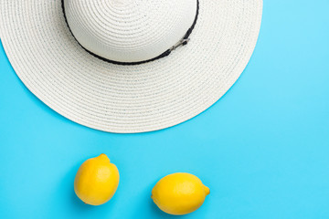 Women's white straw beach hat ripe organic yellow lemons on mint blue background. Summer vacation fun fashion concept. Vibrant color combination. Funky trendy style. Poster flyer template