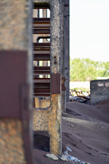 Vertical photo. View of the wall of an industrial building, around is a dark slag from ferrous metallurgy.