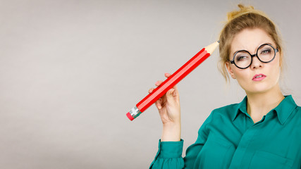 Woman confused thinking, big pencil in hand