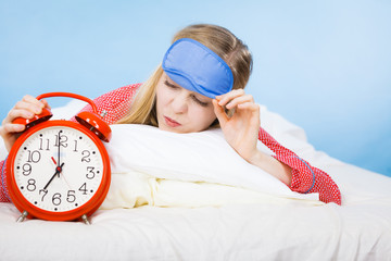 Sleeping woman wearing pajamas holding clock