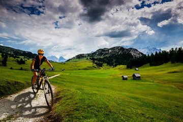 Tourist cycling in Cortina d'Ampezzo, stunning rocky mountains on the background. Man riding MTB enduro flow trail. South Tyrol province of Italy, Dolomites.