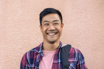 Cool happy man standing outside against the wall