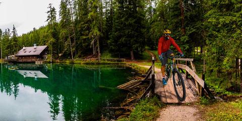 Tourist cycling in Cortina d'Ampezzo, stunning rocky mountains on the background. Man riding MTB enduro flow trail. South Tyrol province of Italy, Dolomites.