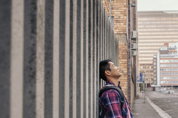 Fototapeta na wymiar Content young Asian man leaning against a wall