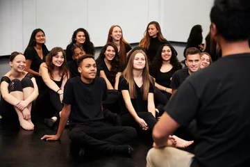Cercles muraux École de danse Teacher At Performing Arts School Talking To Students Sitting On Floor In Rehearsal Studio
