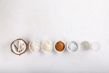 Coconut Products - coconut oil, water, milk, sugar, flakes and flour on white background. Top view. Copy space.