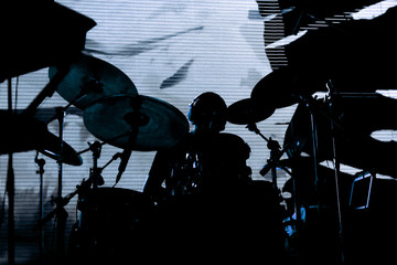 silhouette of a drummer behind the drum set on stage during a concert on the background a screen