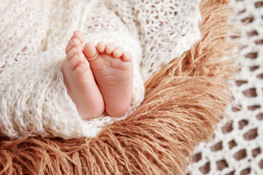 Newborn baby feet on knitted plaid. Closeup picture.