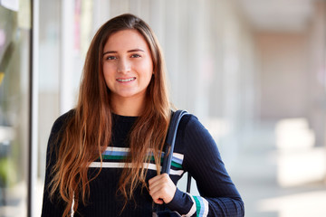 Portrait Of Smiling Female College Student With Backpack In Corridor Of Building