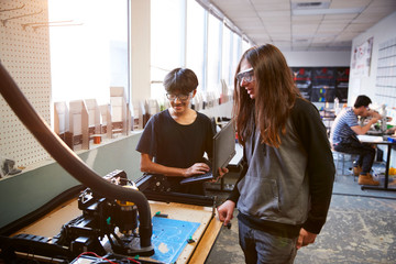 Two Male College Students Work On Computer Controlled Rig In Science Robotics Or Engineering Class