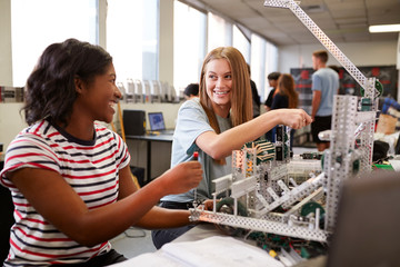 Two Female College Students Building Machine In Science Robotics Or Engineering Class