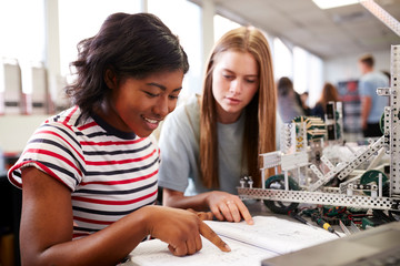 Two Female College Students Building Machine In Science Robotics Or Engineering Class