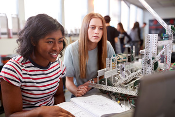 Two Female College Students Building Machine In Science Robotics Or Engineering Class