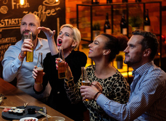Group of friends watching tv in a cafe behind bar counter