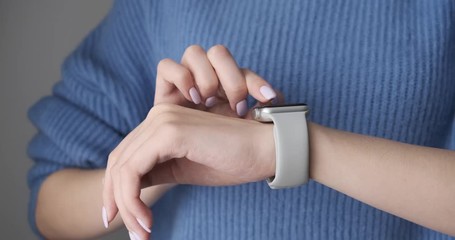 Woman using smartwatch touchscreen wearable technology device. Closeup. Smart watch on female wrist. Pretty girl making gestures on a smartwatch computer device