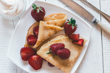 Pancakes with strawberries. On a white wooden background.