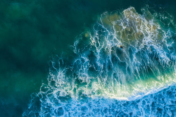 Aerial view - looking down at one surfer in ocean waves at sunset