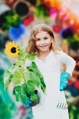 Beatifull girl with sunflower in the garden at summer day. Child relaxing in garden in sunny day. Little gardener playing in garden.