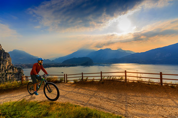 Cycling man riding on bike at sunrise mountains and Garda lake landscape. Cycling MTB enduro flow sentiero ponale trail track. Outdoor sport activity.