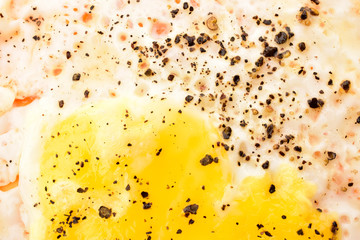 Closeup of half fry egg with balck pepper