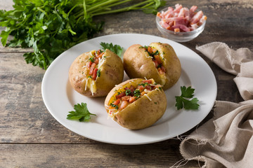 Stuffed potatoes with bacon and cheese on plate on wooden table