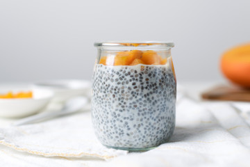 Chia pudding in glass jar with almond milk and mango on white background
