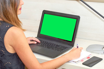 girl working with a notebook at the desk. green screen chroma key.