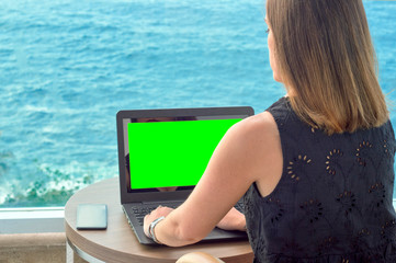 girl working with a notebook on the terrace of a hotel looking at the sea. green screen chroma key.