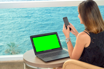 girl working with a notebook on the terrace of a hotel looking at the sea. green screen chroma key.