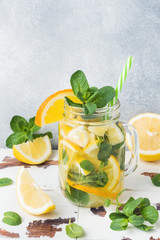 Lemonade drink of soda water, lemon and mint leaves in jar on light background. Copy space