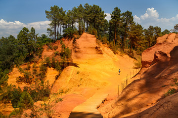 View of the ocher land and a woman climbing the mountain in the park 