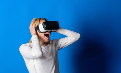 Pretty woman playing game in virtual reality glasses. Funny woman experiencing 3D gadget technology - close up. Amazed young woman touching the air during the VR experience. Virtual reality game.