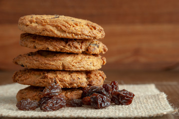 Horizontal close-up of a stack of cookies and raisins on burlap cloth and wooden background