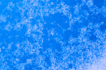 Blue thaw patches in ice and snow on a winter lake