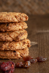 Vertical close-up of a stack of cookies and raisins on dark wooden background