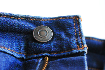 Button on blue denim jeans front isolated on empty white background. Classic simple rivet and blue jeans waistband, unbuttoned jeans front view with metal button close up 