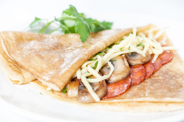 Thin delicious pancake with salami and mushrooms on white