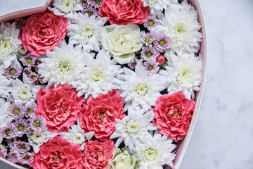 Gift box with heart shaped flowers on grey marble background