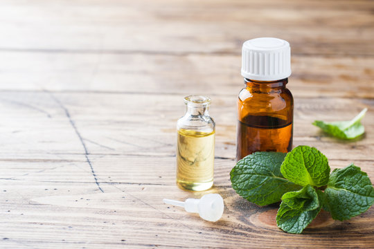 Essential aroma oil with peppermint on wooden background. Selective focus, copy space.
