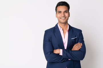 Portrait of young happy Indian businessman in suit smiling with arms crossed - 254393324