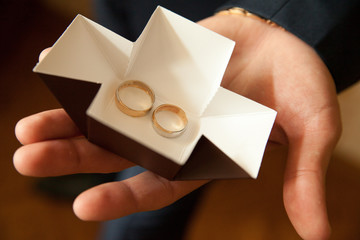 man's hand holds an open box with gold rings