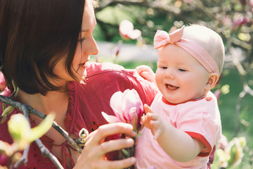 Obraz premium Mother and baby with blooming pink magnolia flower