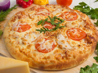 pizza with chicken and tomatoes on a light wooden background