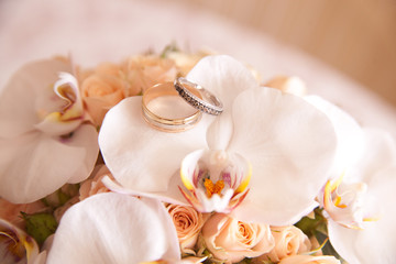 two gold wedding rings lie on a bouquet of flowers, close-up