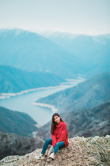 Naklejka na ściany i meble Beautiful Young Girl in a cosy red sweater on Mountain top