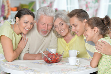 Portrait of big happy family eating fresh strawberries at kitchen