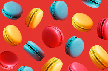 Different types of macaroons in motion falling on a pink background. Turquoise, orange sweet French pastries, close up