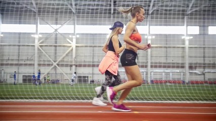 Two young athletic women running in covered area