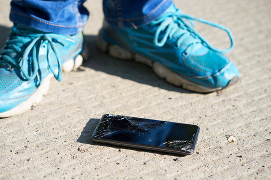 cellphone with broken screen is on the concrete floor after falling down