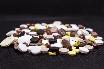 Many different pills unpacked on a black background